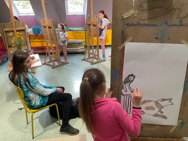 Děti malují u stojanů ve výtvarné dílně